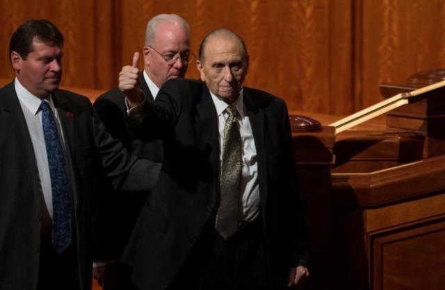 Le président Monson quittant le centre de conférence avec le pouce levé vers la foule à la fin de la session de prêtrise de la conférence générale