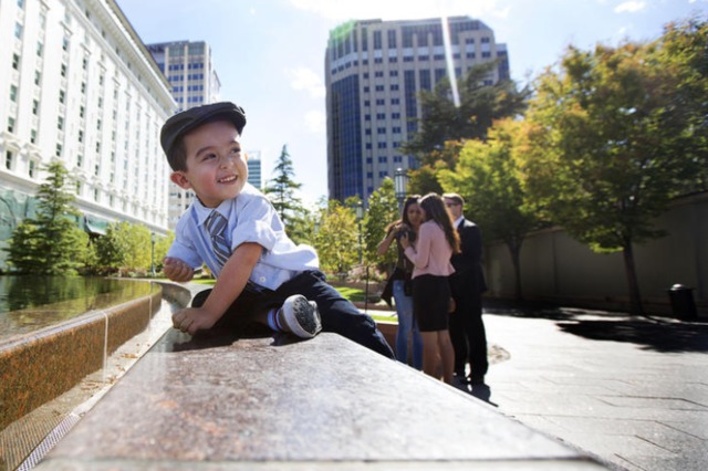Un petit garçon joue près de la fontaine de temple square près du centre de conférence.